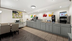 Un área de cocina moderna con comedor, refrigerador, cafetera y dispensador de jugo.
