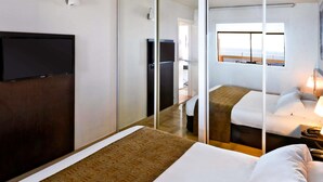 A hotel room with a bed, a TV, a sliding door, and a window with a view. - Aparthotel Adagio Nice Promenade des Anglais (Nice)