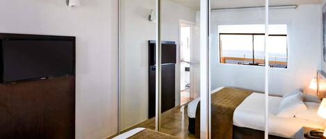 Una habitación de hotel con cama, televisión, puerta corredera y ventana con vistas.