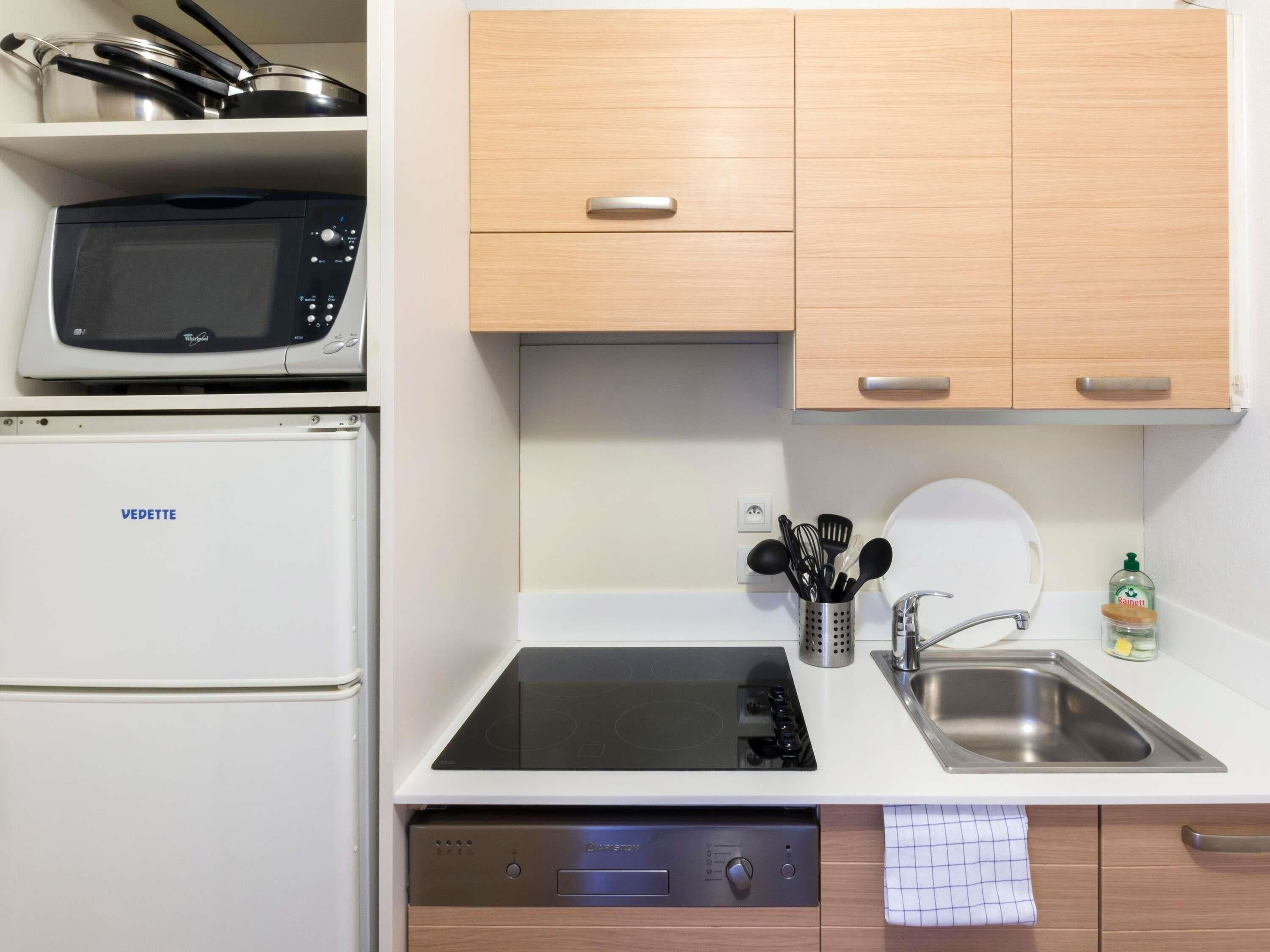 Une cuisine équipée d’un four à micro-ondes, d’un réfrigérateur, d’une cuisinière, d’un évier et d’armoires en bois.