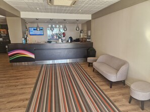 A modern reception area with a striped carpet, a grey sofa, and a reception desk with a digital screen. - Aparthotel Adagio Nice Promenade des Anglais (Nice)