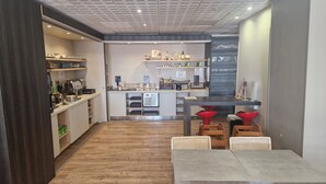 A modern kitchen with wooden flooring, a dining area with a table and chairs, and a bar area with stools. - Aparthotel Adagio Nice Promenade des Anglais (Nice)