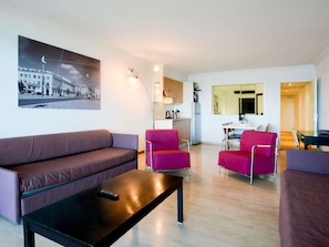 A modern living room with a sofa, armchairs, a coffee table, and a kitchen area in the background. - Aparthotel Adagio Nice Promenade des Anglais (Nice)