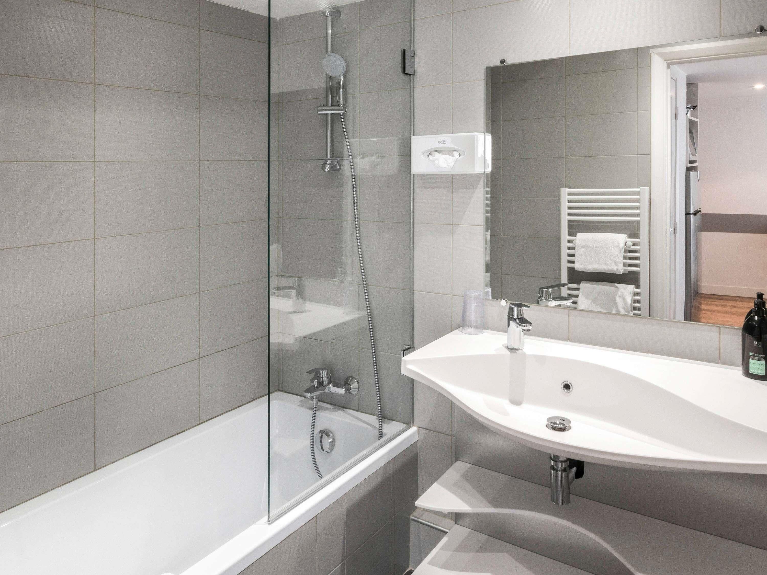 Un baño moderno con cabina de ducha de vidrio, un lavabo blanco y un espejo.