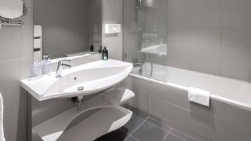Een moderne badkamer met een groot wit wastafel, een spiegel, een douche met glazen wanden en een wit bad.
