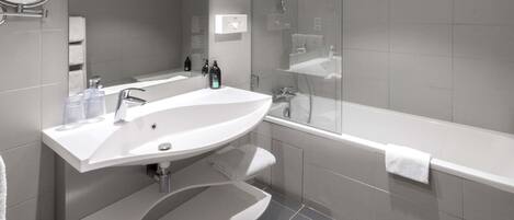 Une salle de bain moderne avec un grand lavabo blanc, un miroir, une douche à l’italienne et une baignoire blanche.