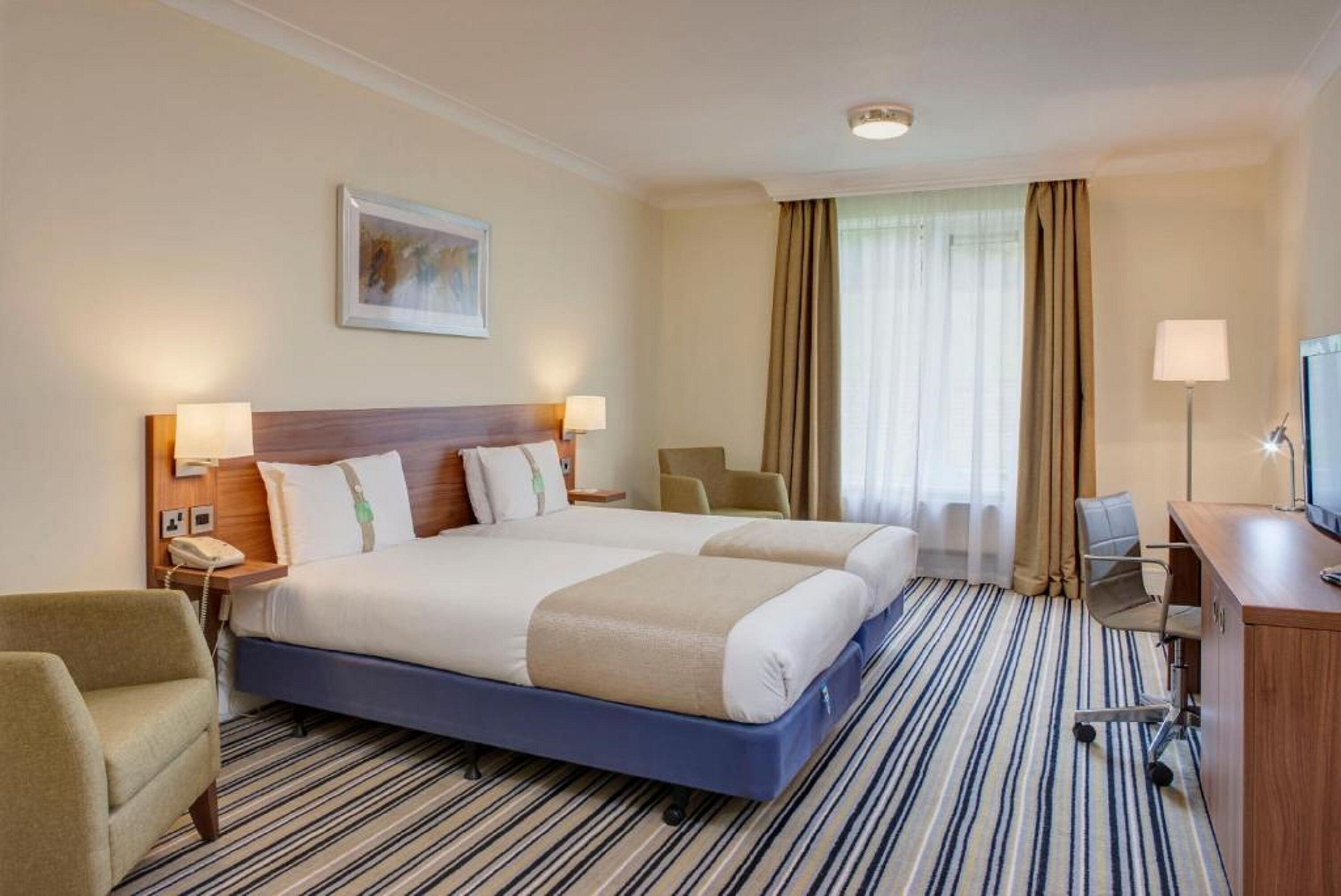 Una habitación de hotel con una cama grande, un escritorio, una silla y un televisor.