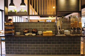 A hotel reception area with a dark tiled counter, various bowls, plates, and a coffee machine. - Holiday Inn Taunton by IHG (Taunton)