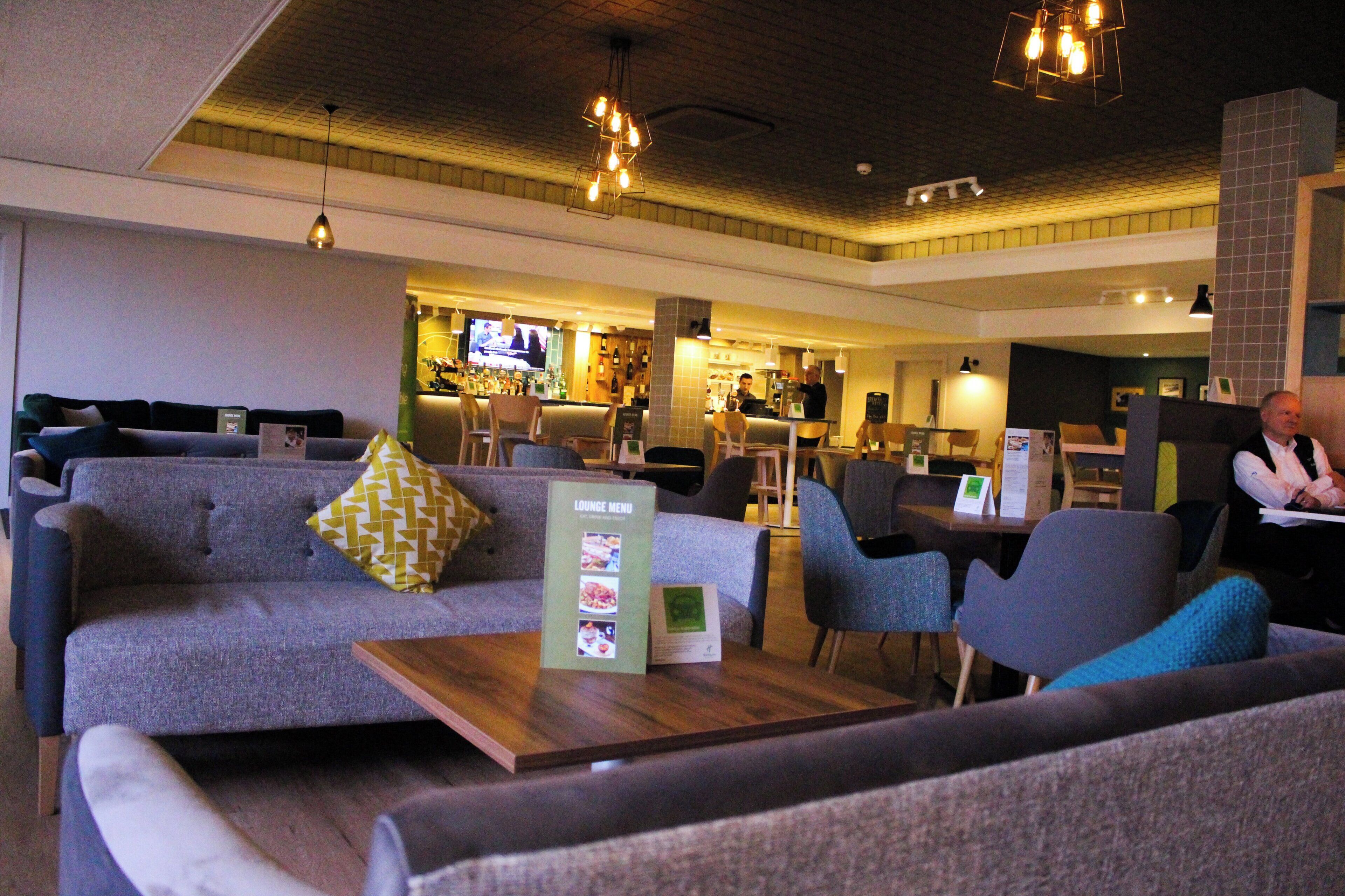 A lounge area with sofas, chairs, and a wooden table with a menu.