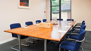A conference room with a long table, blue chairs, a wooden box, and a fire exit sign.