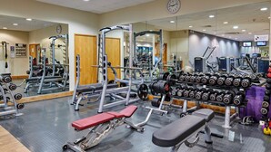 Un gimnasio con diverso equipo de ejercicio, incluyendo mancuernas, bancos y máquinas de pesas.