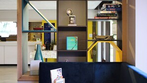 Una habitación con un sofá azul, un trofeo y una estantería llena de juegos de mesa.