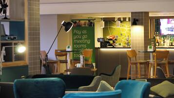 Un vestíbulo de hotel con zonas de estar, una recepción y un bar.
