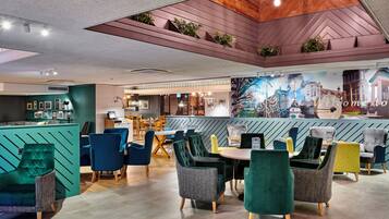 A modern cafe with a variety of seating options, including chairs and tables, and a bar area with a cityscape mural.