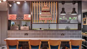 A modern kitchen with a long counter, wooden chairs, and a decorative sign with holiday greetings.