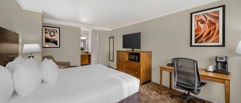 A hotel room with a large bed, a desk with a chair, a television, and a microwave.