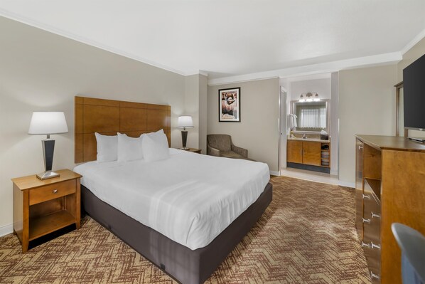 A hotel room with a large bed, a desk, a chair, a vanity with a mirror, and a television. - Best Western Plus Northwoods Inn (Crescent City)