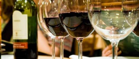 A row of wine glasses filled with red wine on a table.