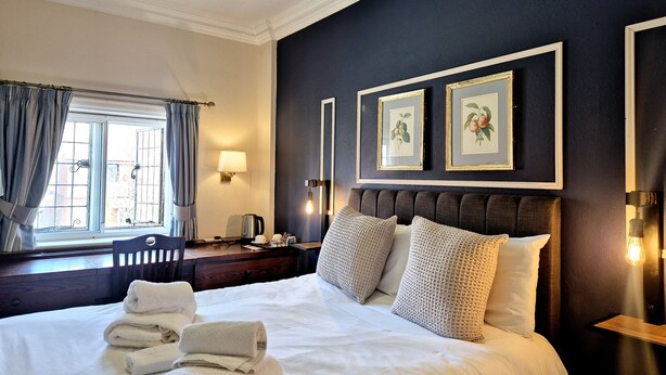 Une chambre d’hôtel avec un grand lit, une table de chevet, une lampe et deux tableaux encadrés au mur.