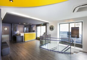 A modern interior with a reception desk, a glass railing, and a view of the sea.