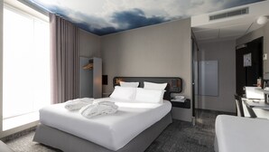 A modern hotel room with a large bed, a desk, and a shower area. - Libertel Montmartre Opéra (Paris)