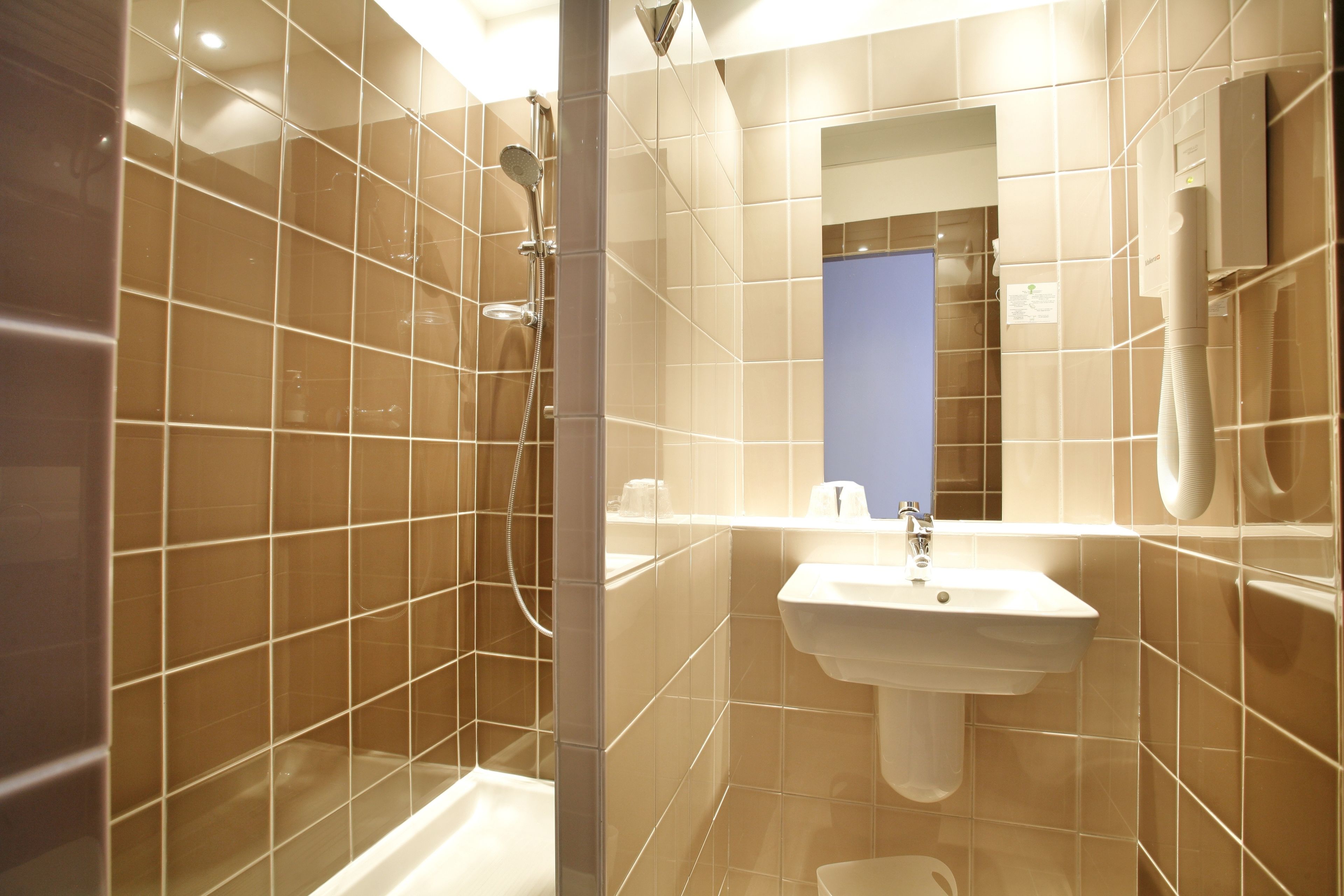 Une salle de bain moderne avec une douche, un lavabo et un miroir.