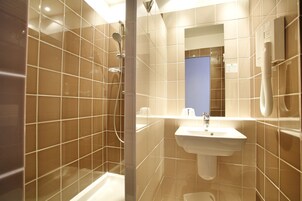 Un baño moderno con ducha, lavamanos y espejo.