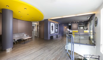 A modern lobby with a grey sofa, a coffee table, and a reception desk.