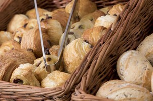 A basket filled with various types of pastries, including croissants and bread rolls.