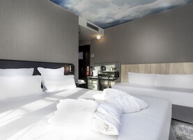 A hotel room with two beds, a minibar, and a ceiling with a cloud design.