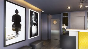A reception area with a modern design, featuring a reception desk, a large framed photograph, and a small vase with flowers. - Libertel Montmartre Opéra (Paris)