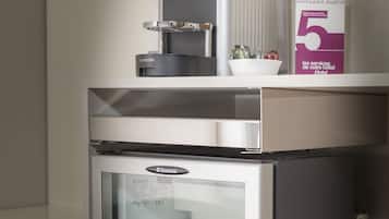 Un minibar con dispensador de agua y un refrigerador que contiene una botella de agua.
