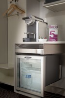 A minibar with a water dispenser and a refrigerator containing a bottle of water.