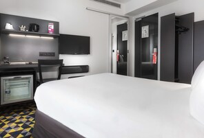 A hotel room with a bed, a desk with a computer, a mini-fridge, a TV, and a microwave.