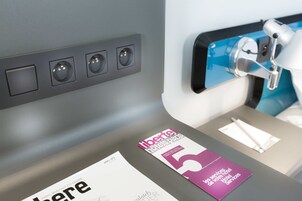 A hotel room with a bed, a bedside table, and a wall-mounted reading light.