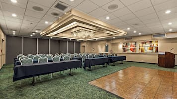 Une salle de conférence avec des rangées de tables et de chaises, un pupitre et des œuvres d’art accrochées aux murs.