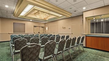 A conference room with rows of chairs, a chandelier, and a wooden counter.