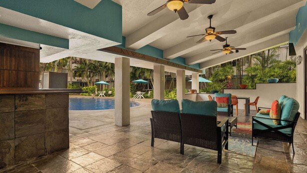 A spacious indoor area with a pool, seating, and ceiling fans. - Airport Honolulu Hotel, Trademark Collection by Wyndham (Honolulu)