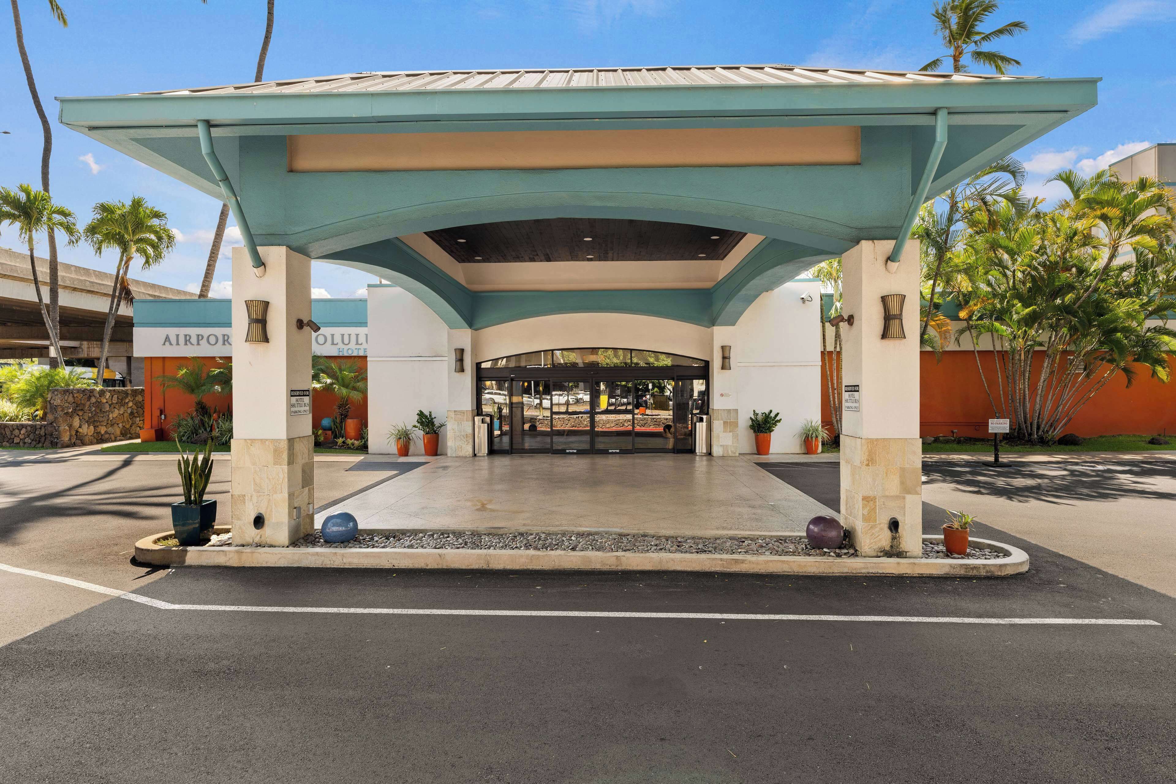 Una entrada cubierta a un hotel con diseño moderno, que presenta un techo plano y un arco central.