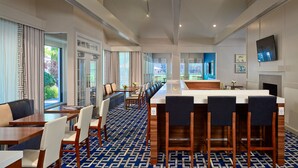 Een moderne hotellobby met een lange receptiebalie, een zithoek en grote ramen met uitzicht op groen.