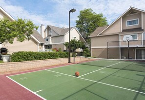 Una cancha de baloncesto al aire libre con aro, rodeada de edificios residenciales.