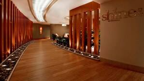 Un pasillo con paneles de madera, un mostrador de recepción y una pared con el texto "shine" y "for Sheraton".