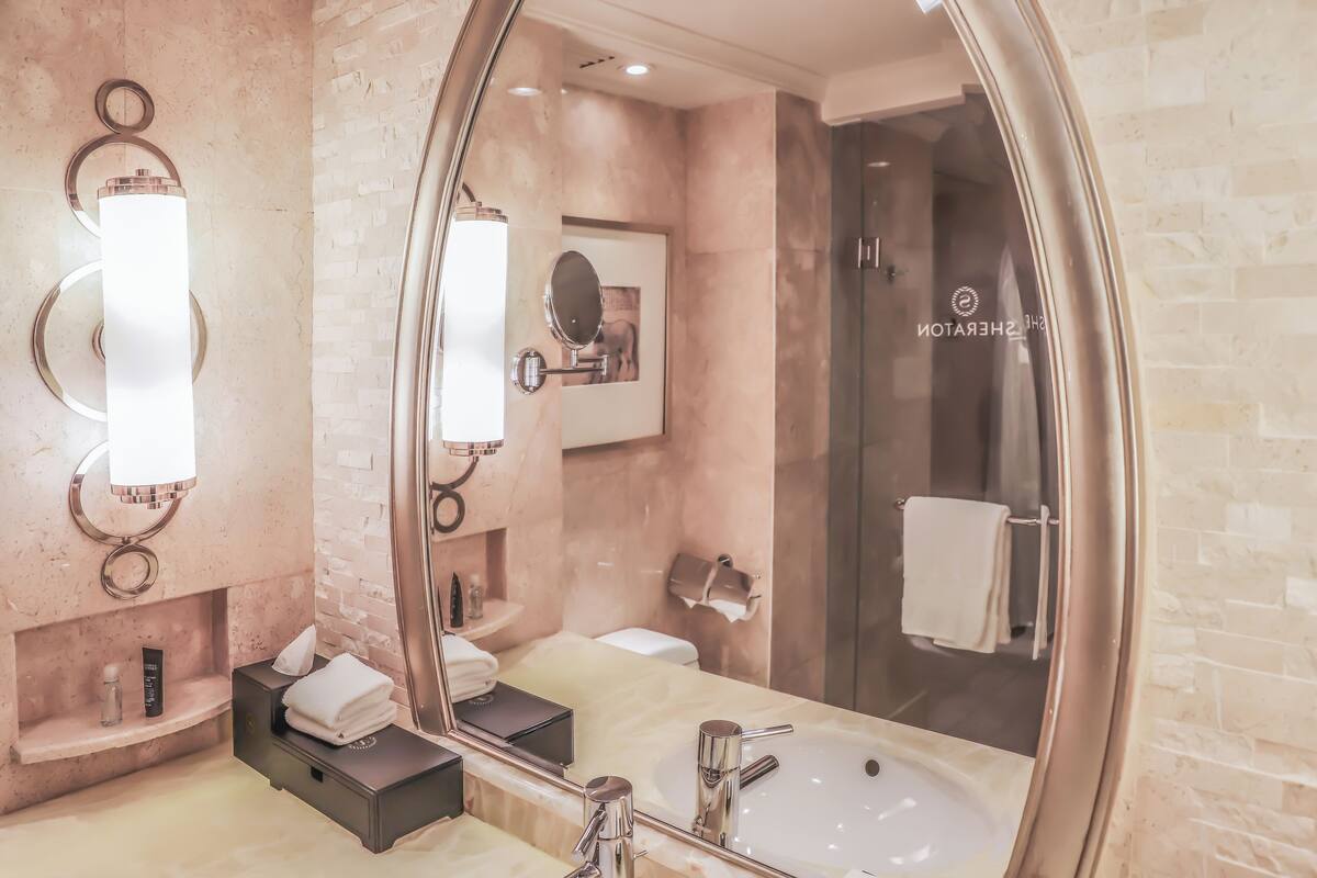 A modern bathroom with a large mirror, a sink, and a shower area.