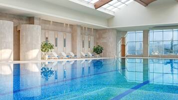 Una piscina techada, sillones reclinables de piscina