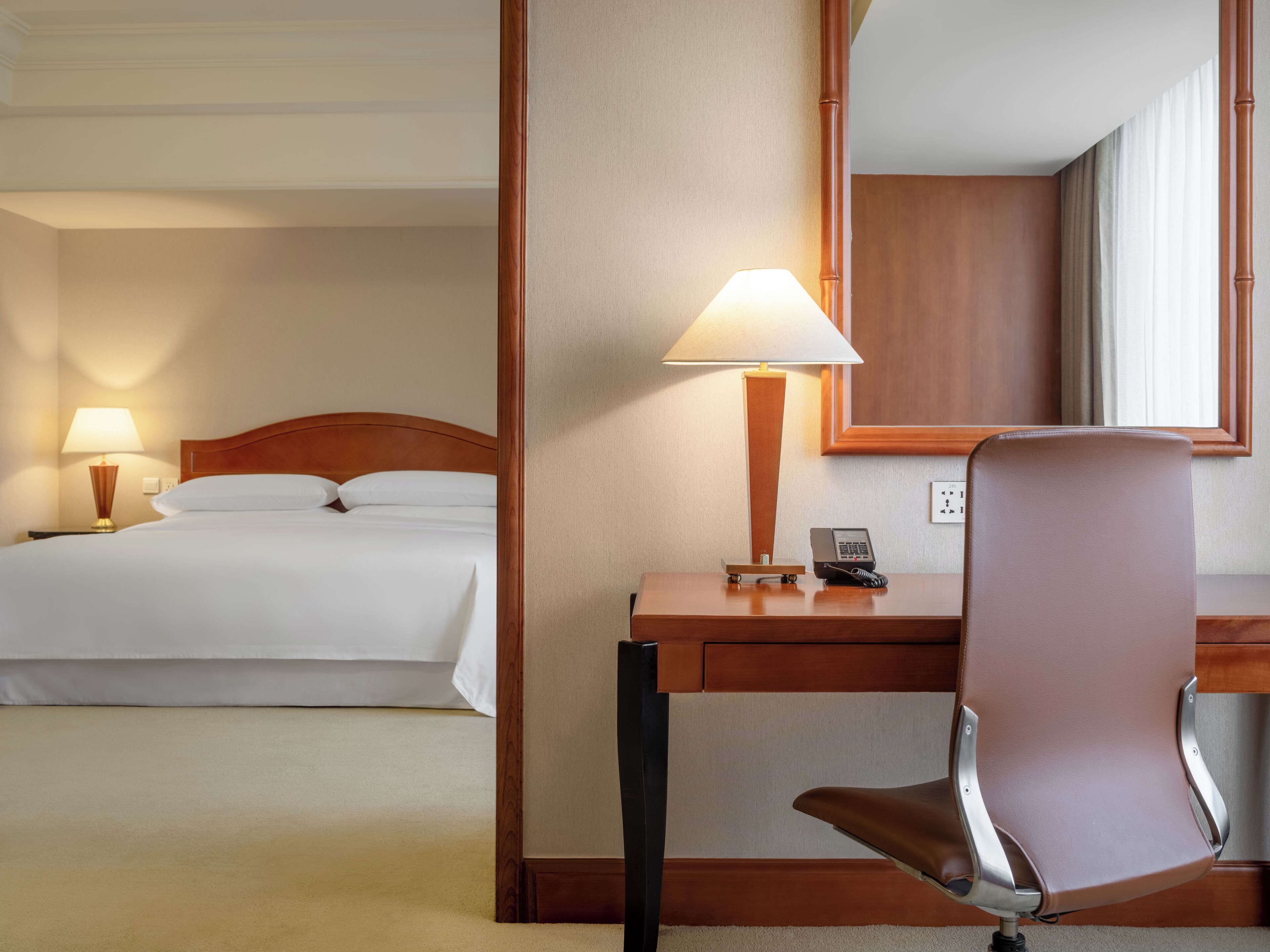 Ein Hotelzimmer mit Bett, Schreibtisch, Lampe, Telefon und Stuhl.