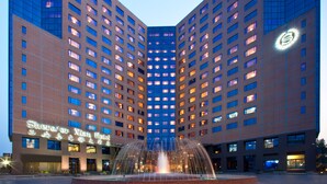 Un hotel con fachada simétrica, varios pisos y una fuente central.