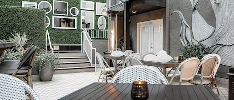 An outdoor patio with wicker furniture, a table with a candle, and a mural on the wall.
