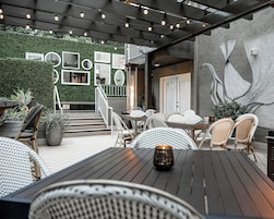 Un patio al aire libre con mobiliario de mimbre, una mesa con una vela y un mural en la pared.
