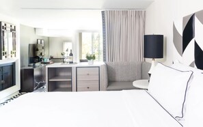 Una habitación de hotel moderna con cama, escritorio, sofá y televisor.