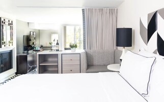 Una habitación de hotel moderna con cama, escritorio, sofá y televisor.